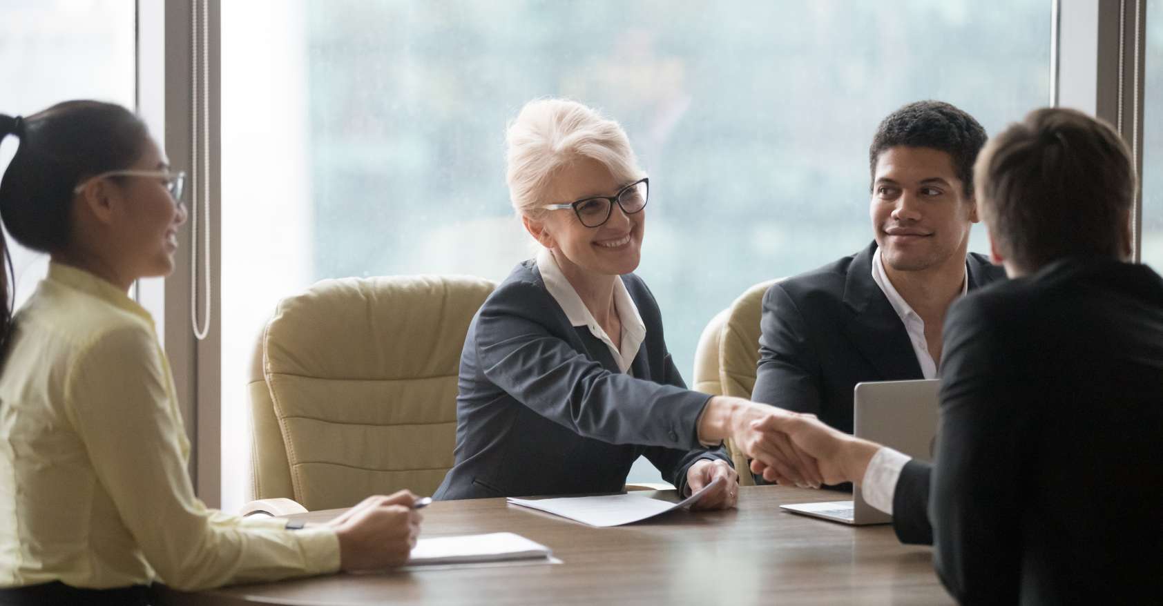 Older woman job candidate shakes hands in group interview