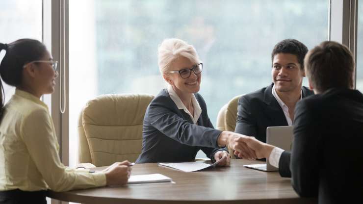Older woman job candidate shakes hands in group interview