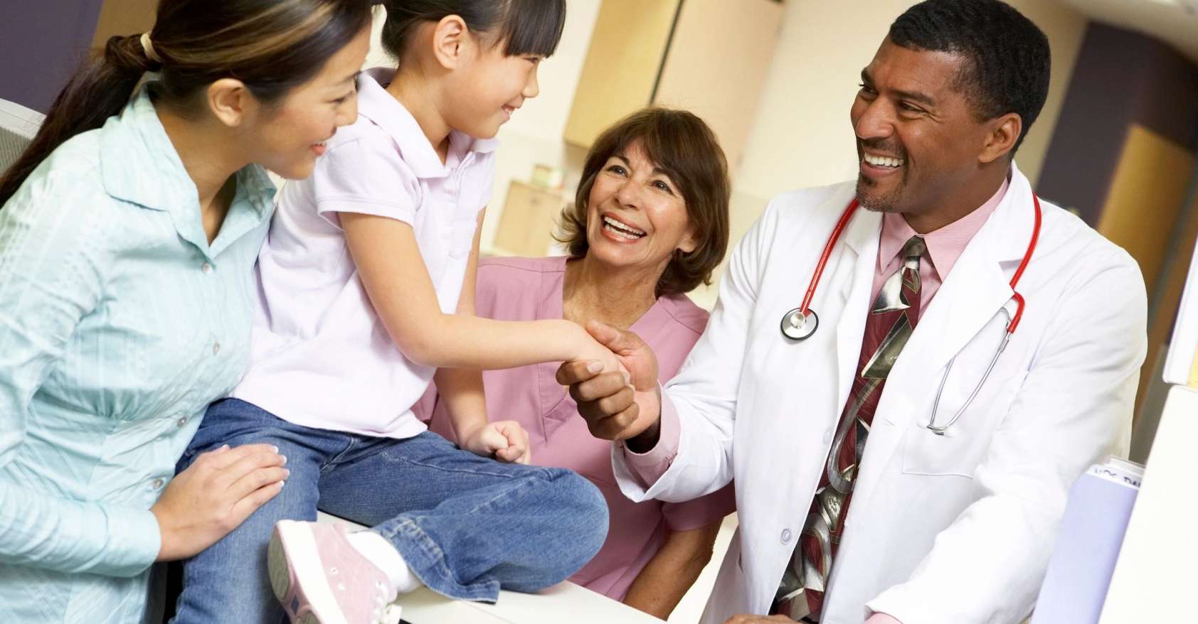 Mother and child shake hands with doctor and nurse