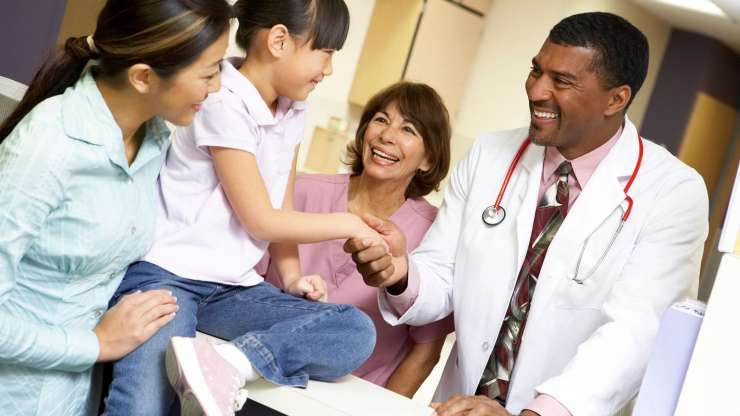 Mother and child shake hands with doctor and nurse